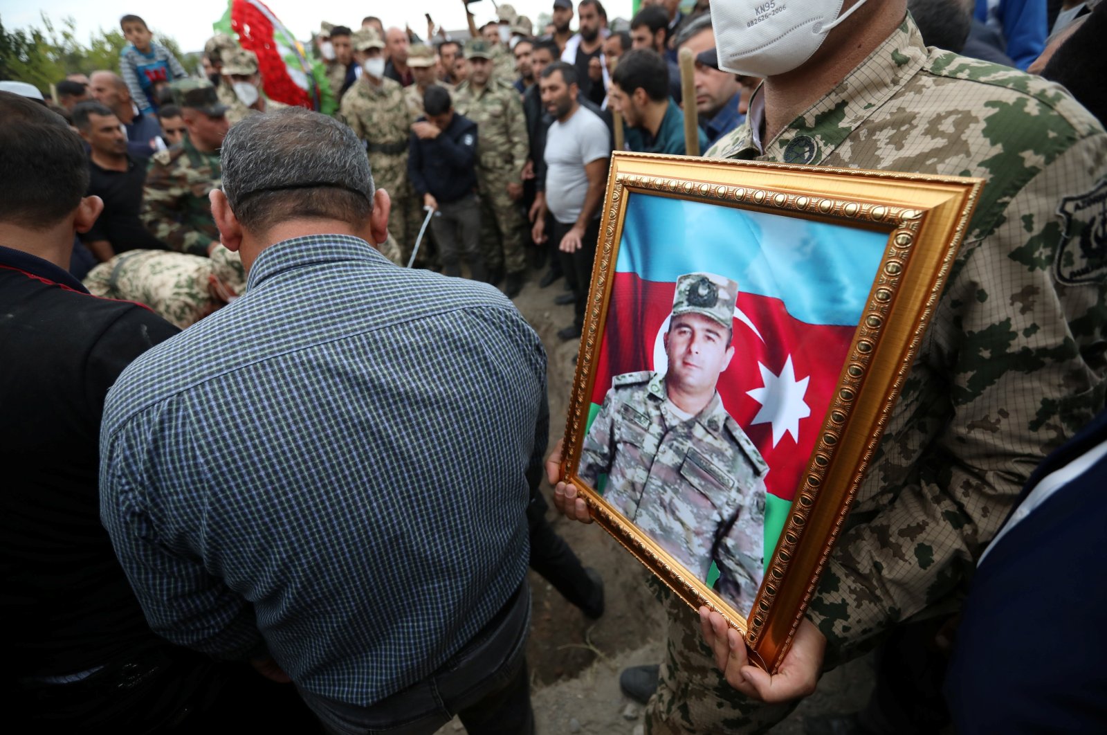 A servicemen holds a portrait of Colonel Lieutenant Makhman Ganbarov, who was killed during the fighting in Armenia-occupied Nagorno-Karabakh region, during a funeral in the city of Barda, Azerbaijan Oct. 1, 2020. (Reuters Photo)