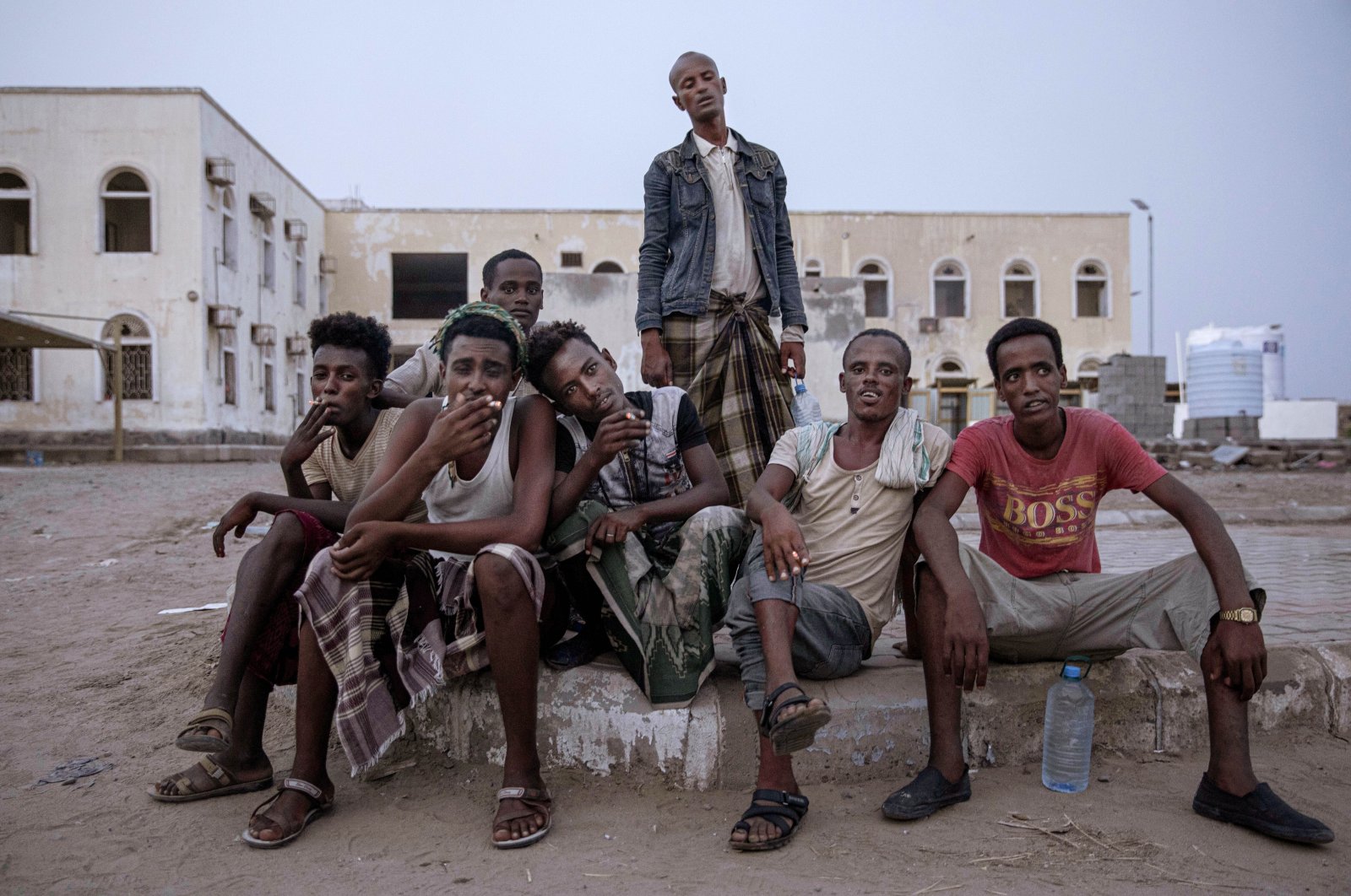 Ethiopian migrants sit together and smoke, as they take shelter in the "22nd May Football Stadium," destroyed by war, in Aden, Yemen, July 21, 2019. (AP Photo)