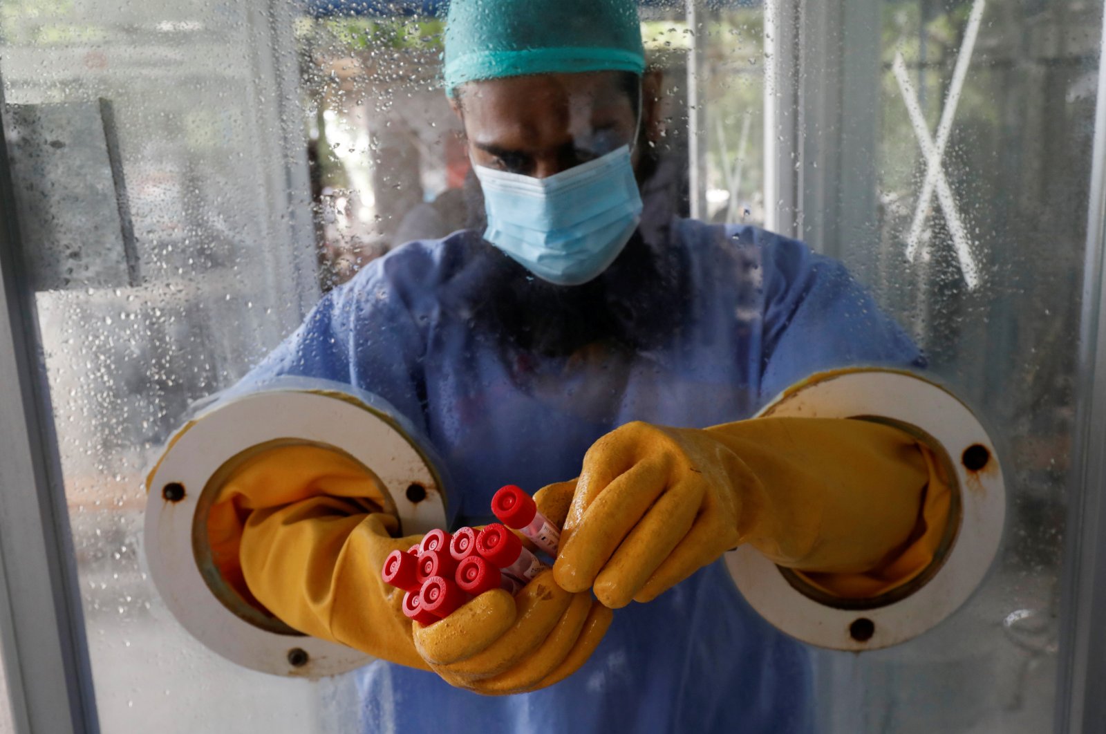 A paramedic wearing protective gear at a glass booth counts nose-swab samples to be tested for COVID-19, in Karachi, Pakistan, June 26, 2020. (Reuters Photo)