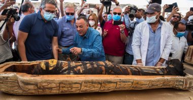  A picture taken on October 3, 2020 shows Egyptian Minister of Tourism and Antiquities Khaled Al-Anani (L), and Mustafa Waziri (R), Secretary General of the Supreme Council of Antiquities, unveil the mummy inside a sarcophagus excavated by the Egyptian archaeological mission working at the Saqqara necropolis, (AFP Photo)