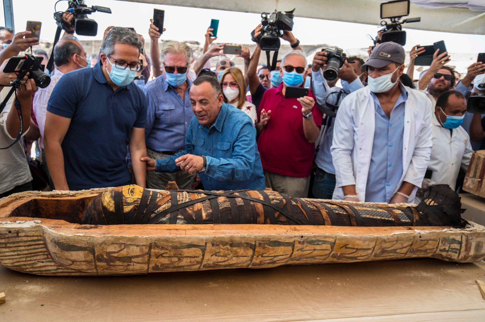  A picture taken on October 3, 2020 shows Egyptian Minister of Tourism and Antiquities Khaled Al-Anani (L), and Mustafa Waziri (R), Secretary General of the Supreme Council of Antiquities, unveil the mummy inside a sarcophagus excavated by the Egyptian archaeological mission working at the Saqqara necropolis, (AFP Photo)