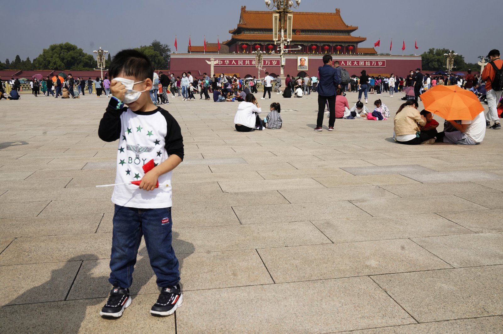 A child covers his eyes with his mask during a visit to Tiananmen Square on National Day in Beijing on Oct. 1, 2020. (AP Photo)