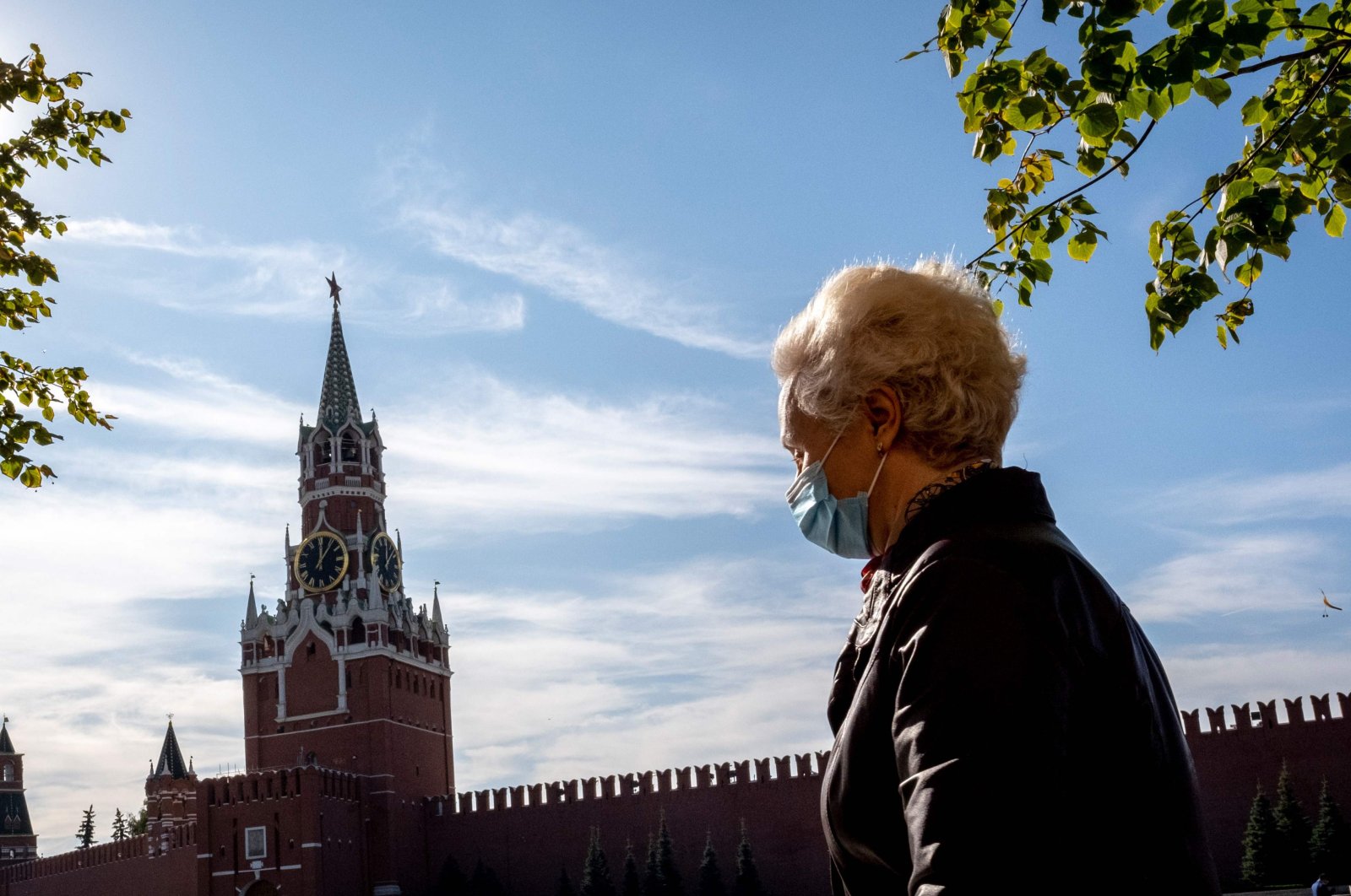 A woman wearing a face mask to protect against the coronavirus disease walks along Red Square with the Kremlin's Spasskaya Tower on the background in central Moscow, Oct. 2, 2020. (AFP Photo)