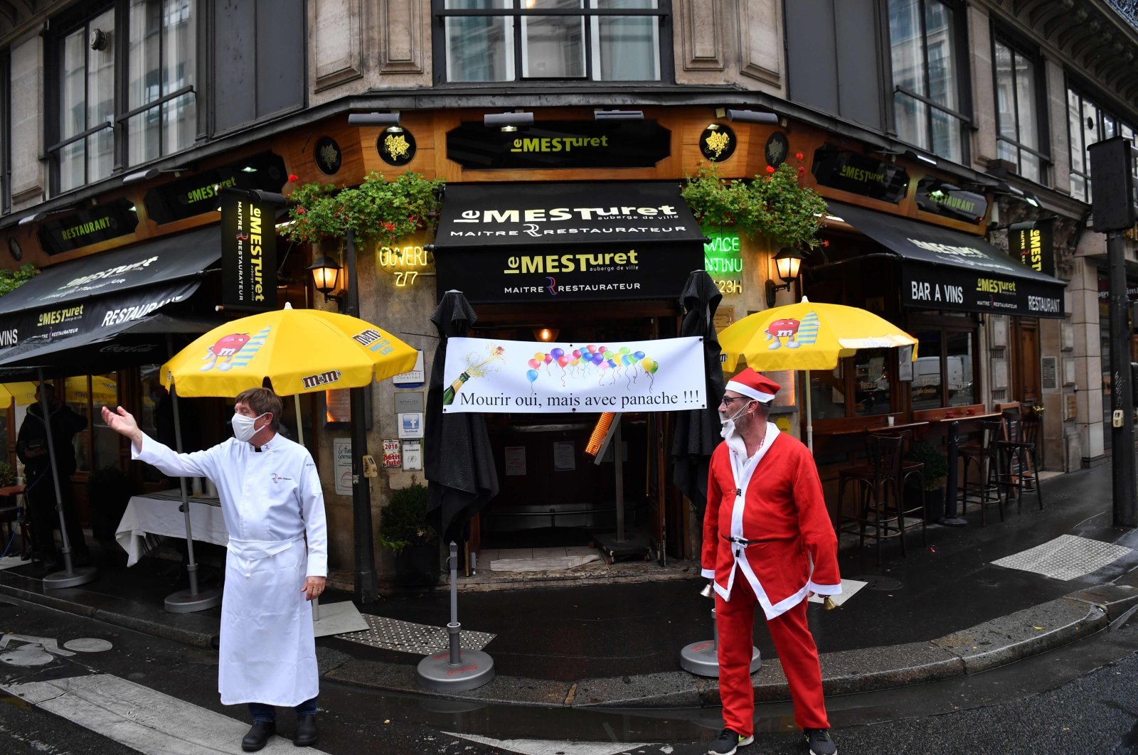 Restaurant owners stand next to a banner reading "To die, yes, but with panache!" in front of "Le Mesturet" restaurant in Paris on Oct. 2, 2020, to protest after the French government imposed fresh curbs to limit the spread of the Covid-19 diseases caused by the novel coronavirus. (AFP Photo)