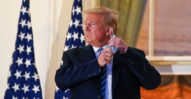 U.S. President Donald Trump pulls off his protective face mask as he poses atop the Truman Balcony of the White House after returning from being hospitalized at Walter Reed Medical Center for COVID-19 treatment, in Washington, D.C., U.S., Oct. 5, 2020. (Reuters Photo)