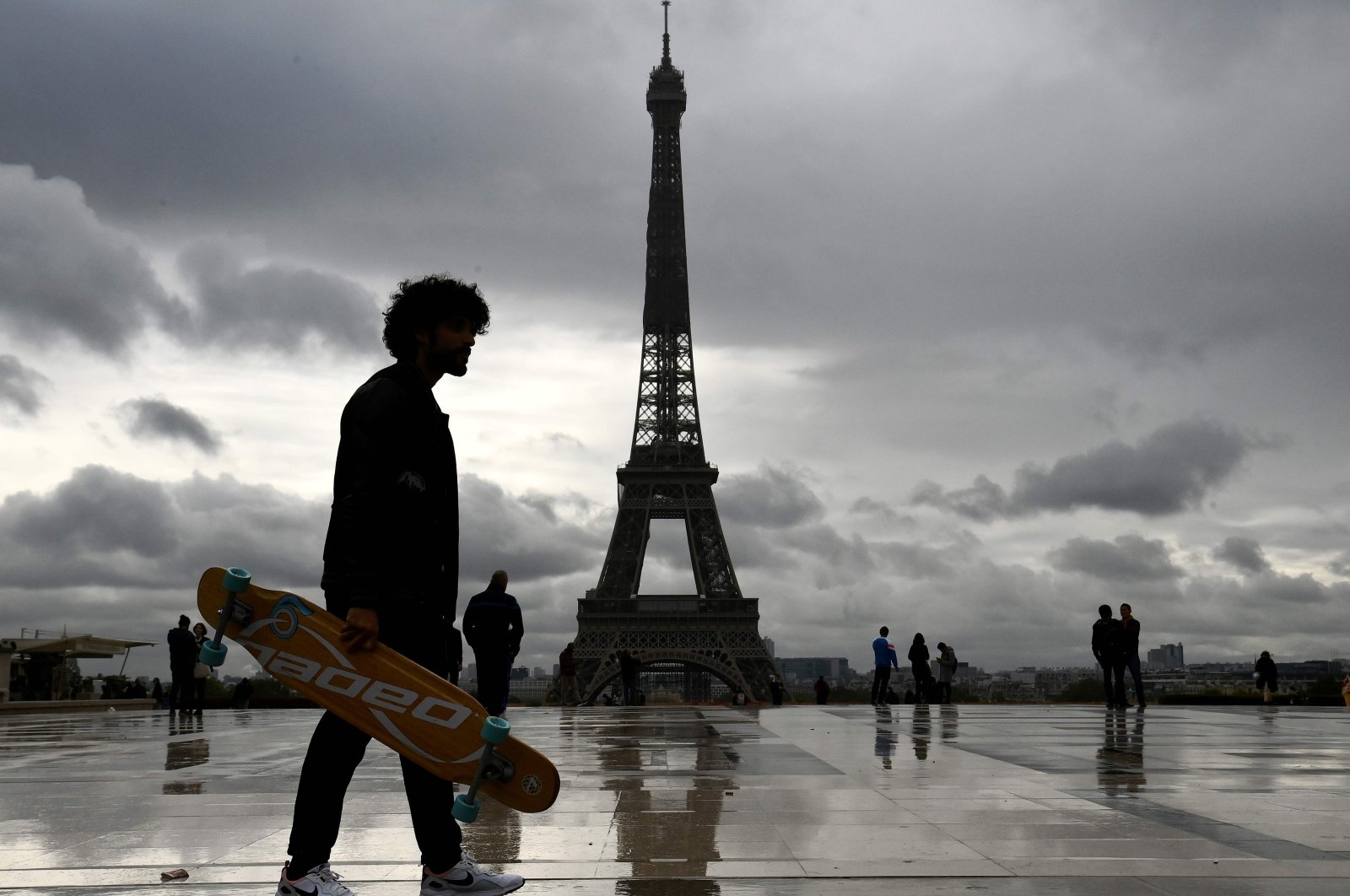 A man stands holding a longboard on the Trocadero Esplanade, as the Eiffel Tower is seen in the background, in Paris, France, Sept. 30, 2020. (AFP Photo)