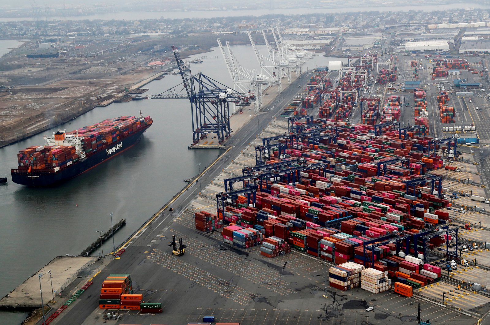 A container ship floats near hundreds of shipping containers stacked at a pier at the Port of New York and New Jersey in Elizabeth, New Jersey, U.S., March 30, 2020. (Reuters Photo)