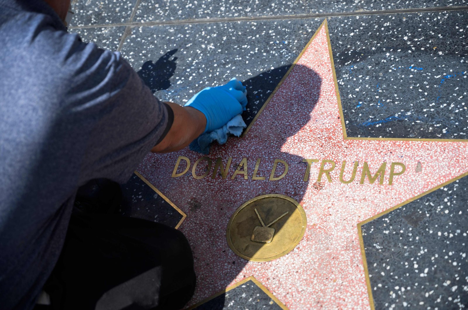 In this file photo a maintenance worker uses cleaning product to remove graffiti after Donald Trump's star on the Hollywood Walk of Fame was defaced, in a mostly empty Hollywood, California, April 23, 2020, during the coronavirus COVID-19 pandemic. (AFP Photo)
