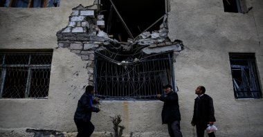 Local residents stand in front of their damaged home hit by artillery fire during the fighting over Nagorno-Karabakh in the city of Terter, Azerbaijan, Oct. 6, 2020. (REUTERS Photo)