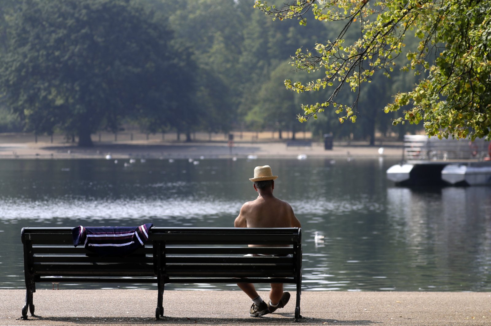 A man sits on a bench at The Serpentine in Hyde Park in London, Britain, Aug. 12, 2020. (AP Photo)