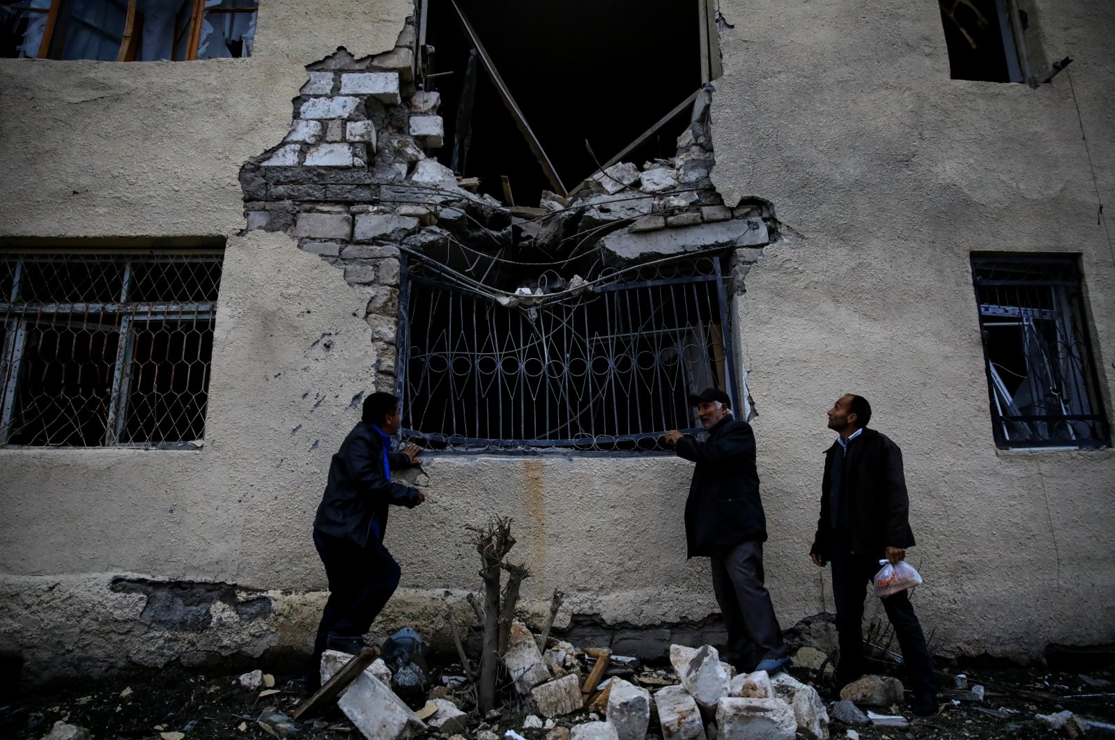 Local residents stand in front of their damaged home hit by artillery fire during the fighting over Nagorno-Karabakh in the city of Terter, Azerbaijan, Oct. 6, 2020. (REUTERS Photo)