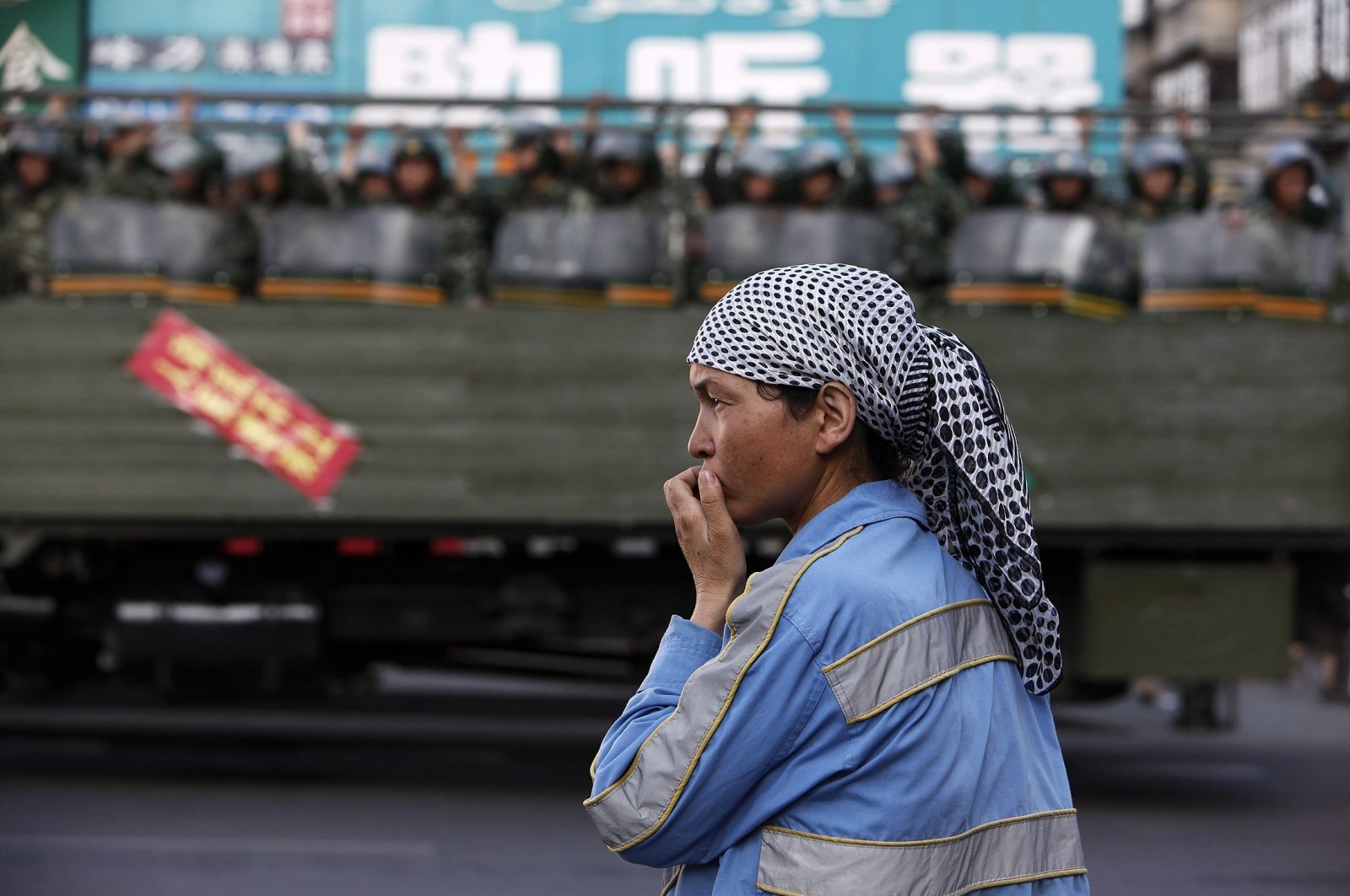 Eine ethnische uigurische Frau steht am Straßenrand, während chinesische Truppen auf einem Lastwagen auf einer Hauptstraße in Ürümqi, Chinas Autonome Region Xinjiang, am 9. Juli 2009 bereitstehen. (Reuters Photo)
