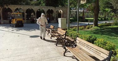 A worker disinfects benches as a precaution against COVID-19 at Balıklıgöl, a popular tourist attraction in Şanlıurfa, southeastern Turkey, Oct. 8, 2020. (AA Photo) 