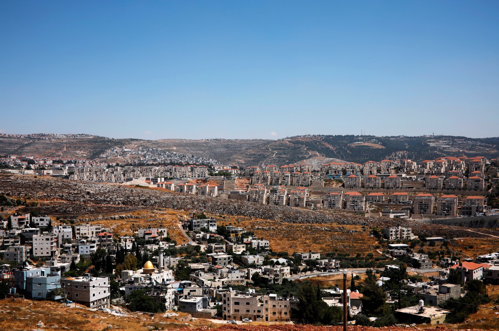 A general view shows Palestinian houses in the village of Wadi Fukin with the Israeli settlement of Beitar Illit in the background, in the occupied West Bank, June 19, 2019. (Reuters Photo)