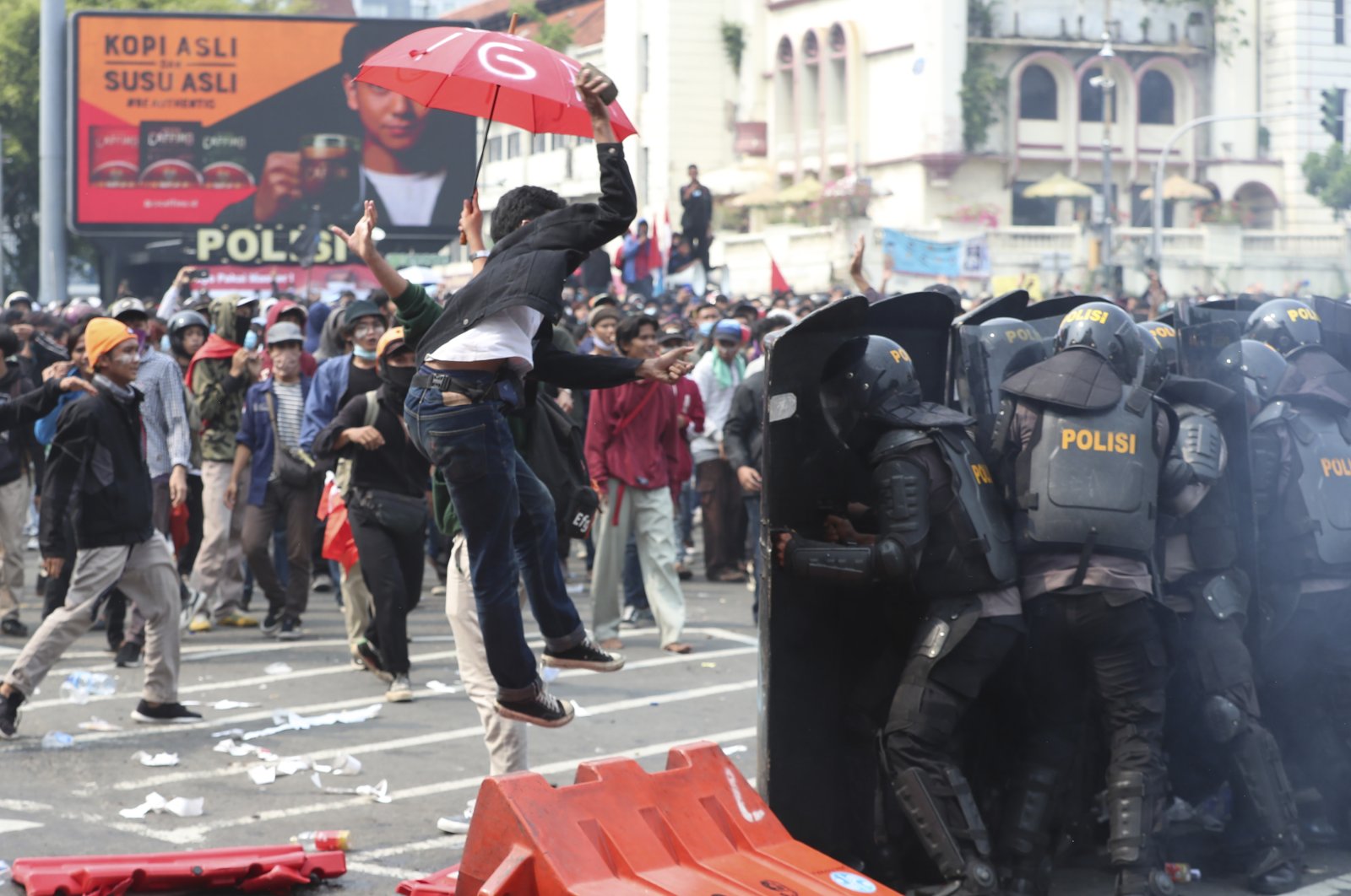 A protester tries to hurl a brick toward police trying block protesters from advancing on the presidential palace during a rally in Jakarta, Indonesia, Oct. 8, 2020. (AP Photo)