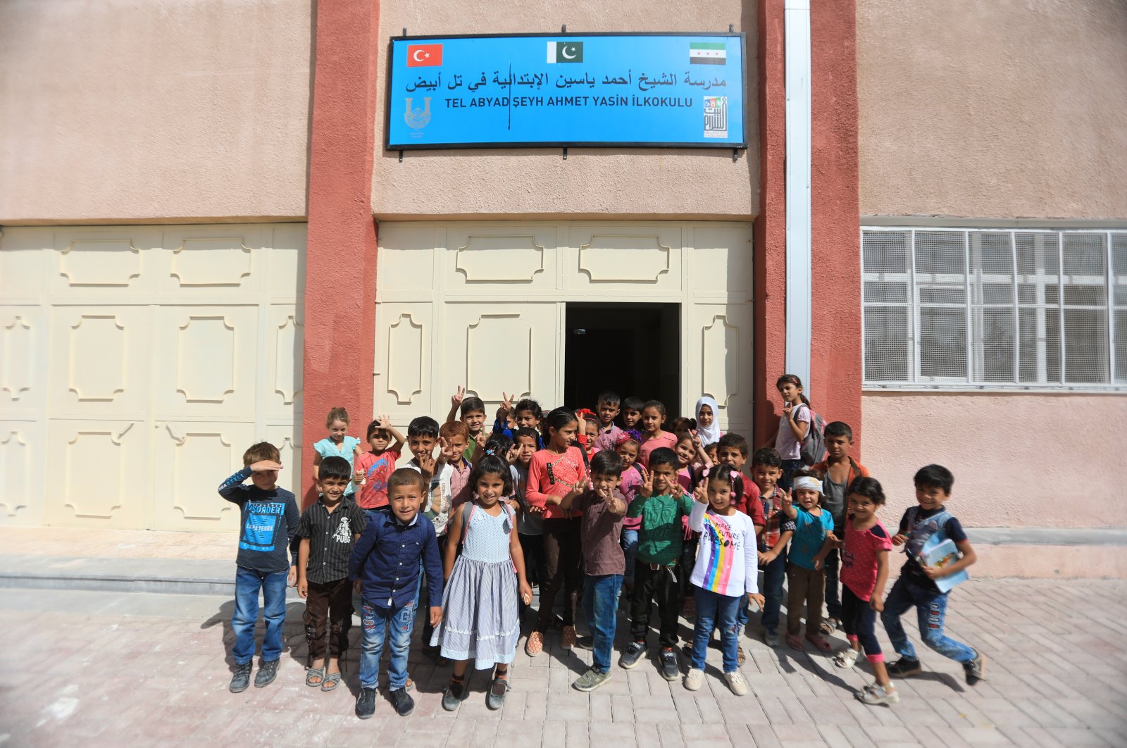 Children pose in front of a reconstructed school in Tal Abyad, Oct.8, 2020. (AA)