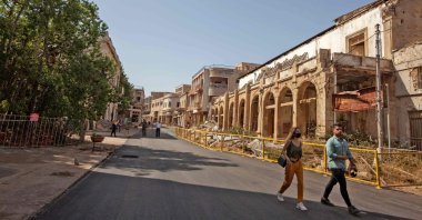 A man and a mask-clad woman walk past abandoned buildings along a street in Varosha (Maraş) on the divided island of Cyprus, Oct. 8, 2020. (AFP Photo)