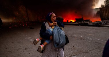 A migrant holds a girl as they flee a fire burning in the Moria camp on the island of Lesbos, Greece, Sept. 9, 2020. (AFP Photo)