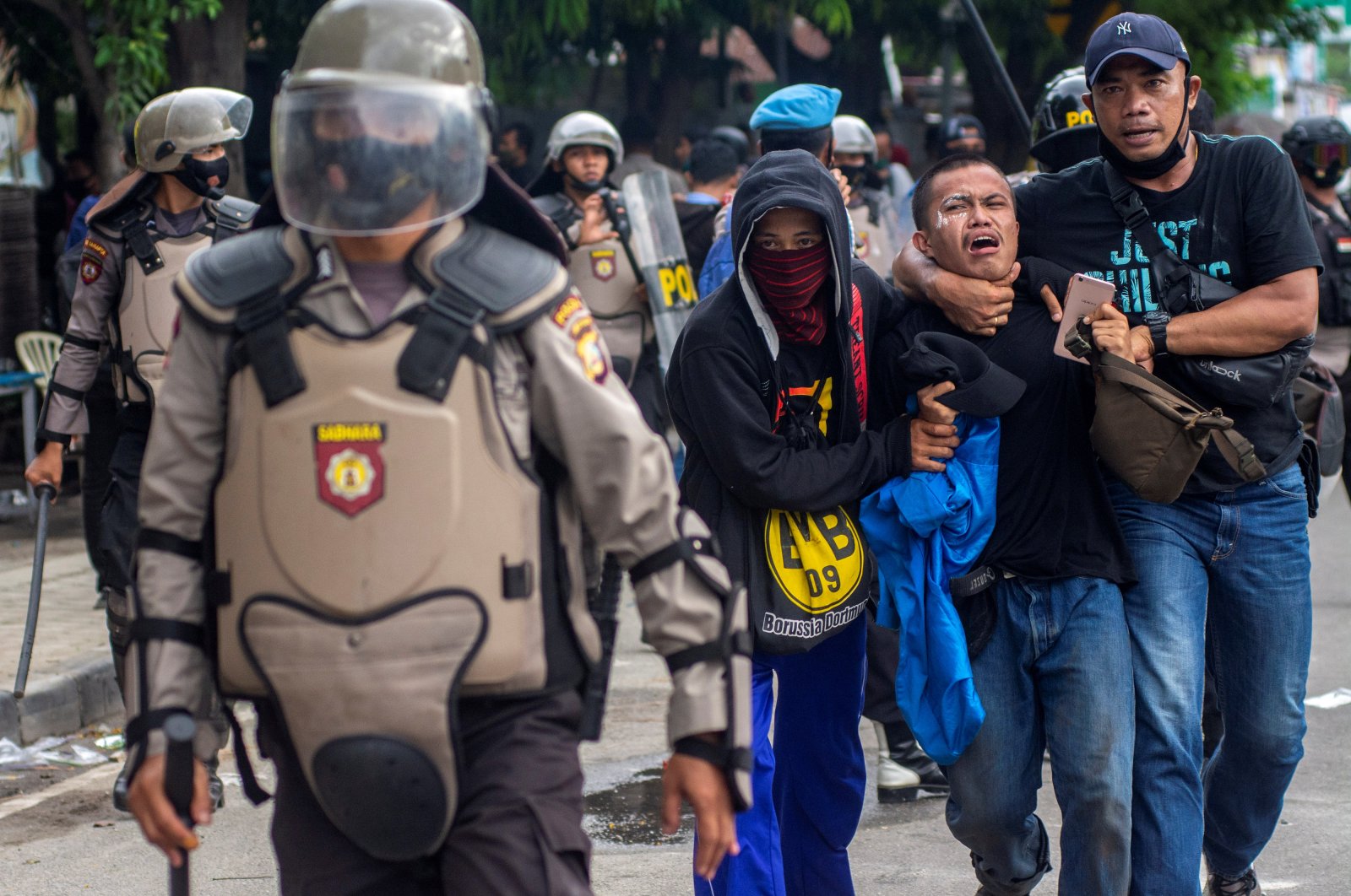 Plainclothes police officers detain a student-demonstrator during a protest against the government's labor reforms in a controversial jobs creation law, outside the regional parliament building in Palu, Central Sulawesi province, Indonesia, Oct. 8, 2020. (Antara Foto/Basri Marzuki/ via Reuters)