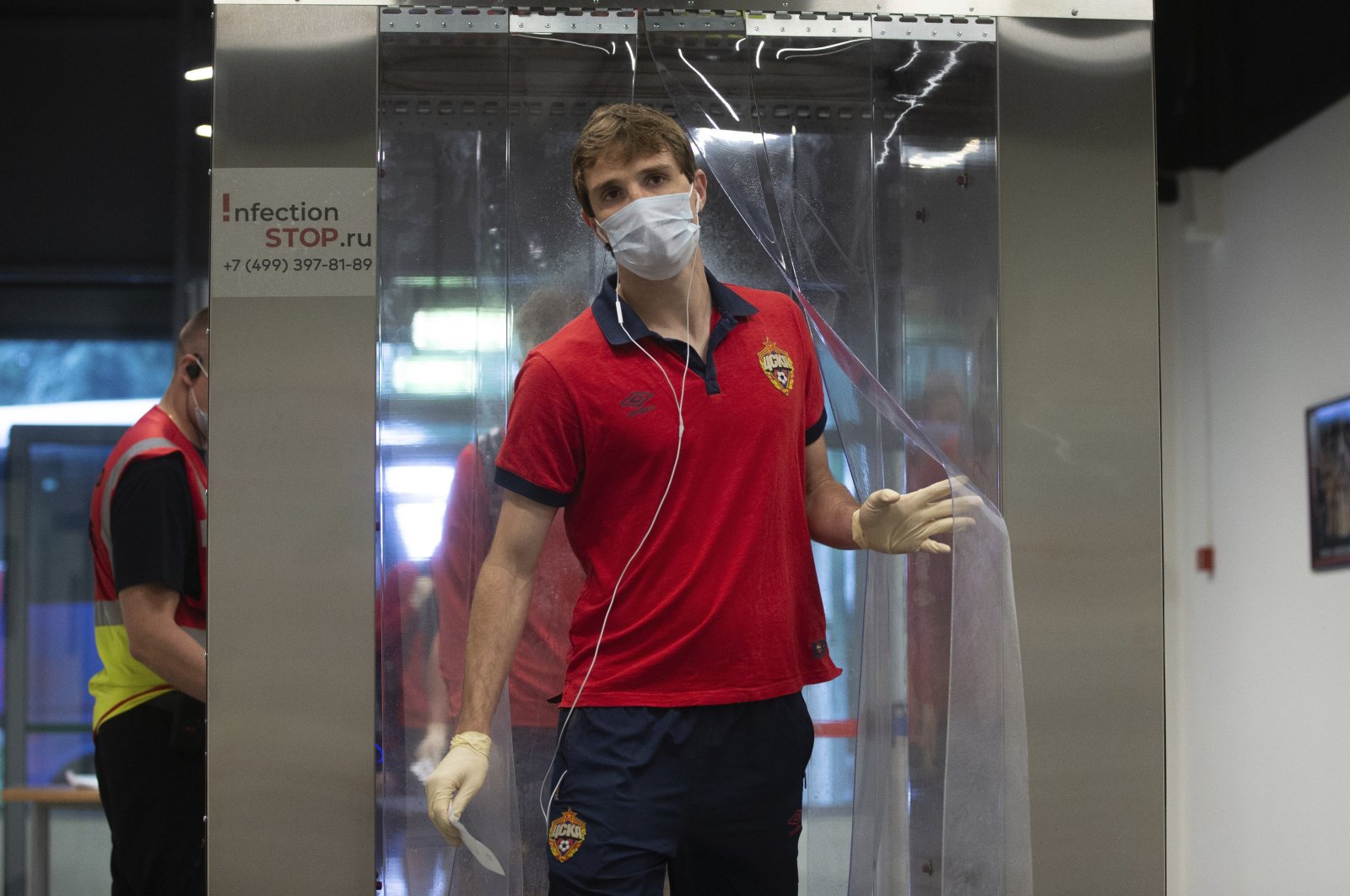 CSKA's Mario Fernandes, wearing face mask and gloves, passes through a disinfection tunnel to protect the spread of coronavirus before the Russia Soccer Premier League soccer match between CSKA Moscow and Zenit St. Petersburg at CSKA Arena in Moscow, Russia, June 20, 2020. (Denis Tyrin, PFC CSKA Pool photo via AP)
