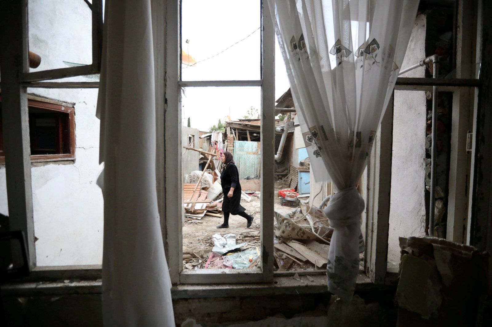A woman walks past a house damaged by recent Armenian shelling in the city of Ganja, Azerbaijan, Oct. 6, 2020. (Reuters Photo)
