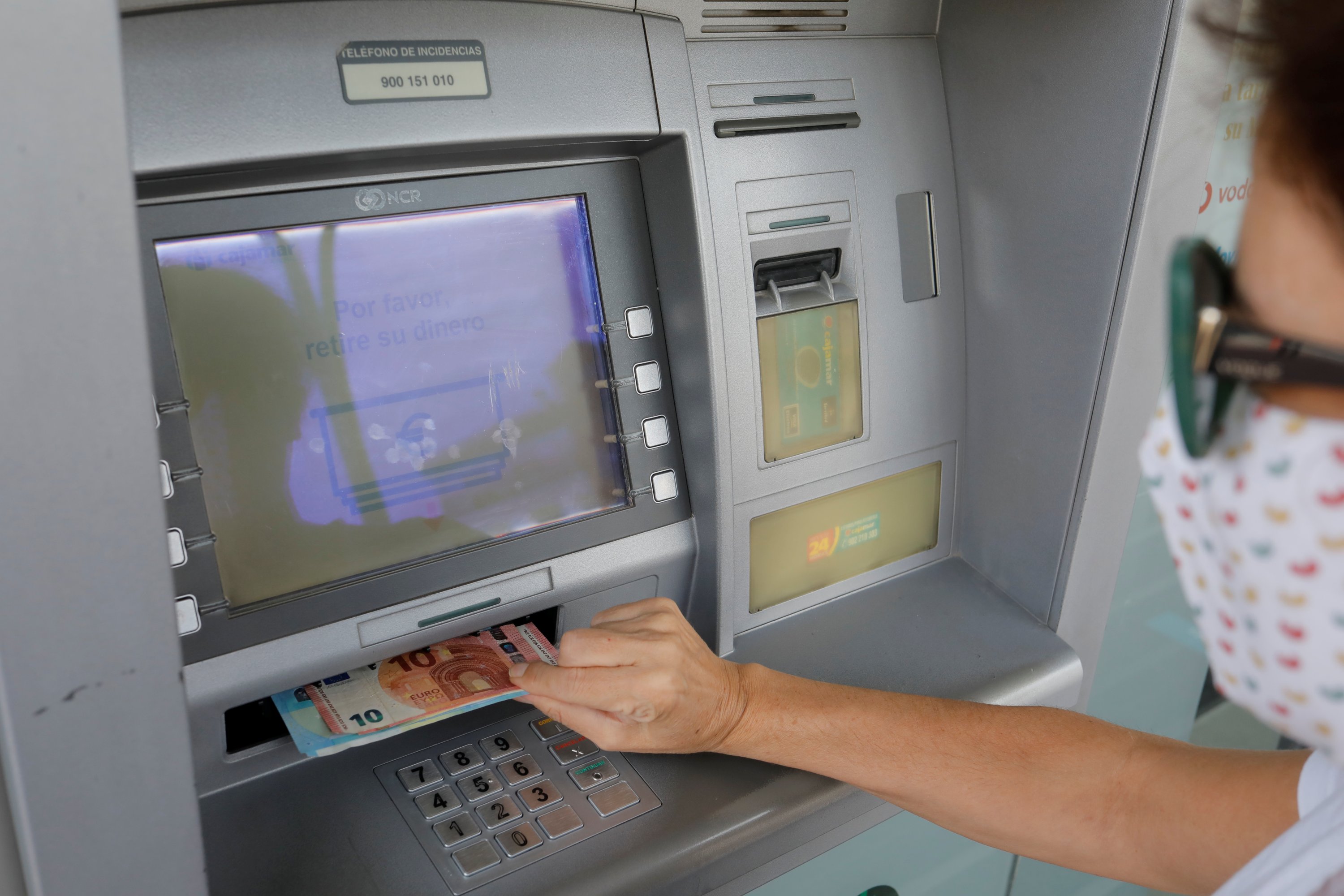 A woman wearing a protective mask withdraws Euro banknotes from an ATM machine at a Cajamar bank branch, amid the coronavirus disease (COVID-19) outbreak, in Ronda, southern Spain, October 9, 2020. (REUTERS Photo)