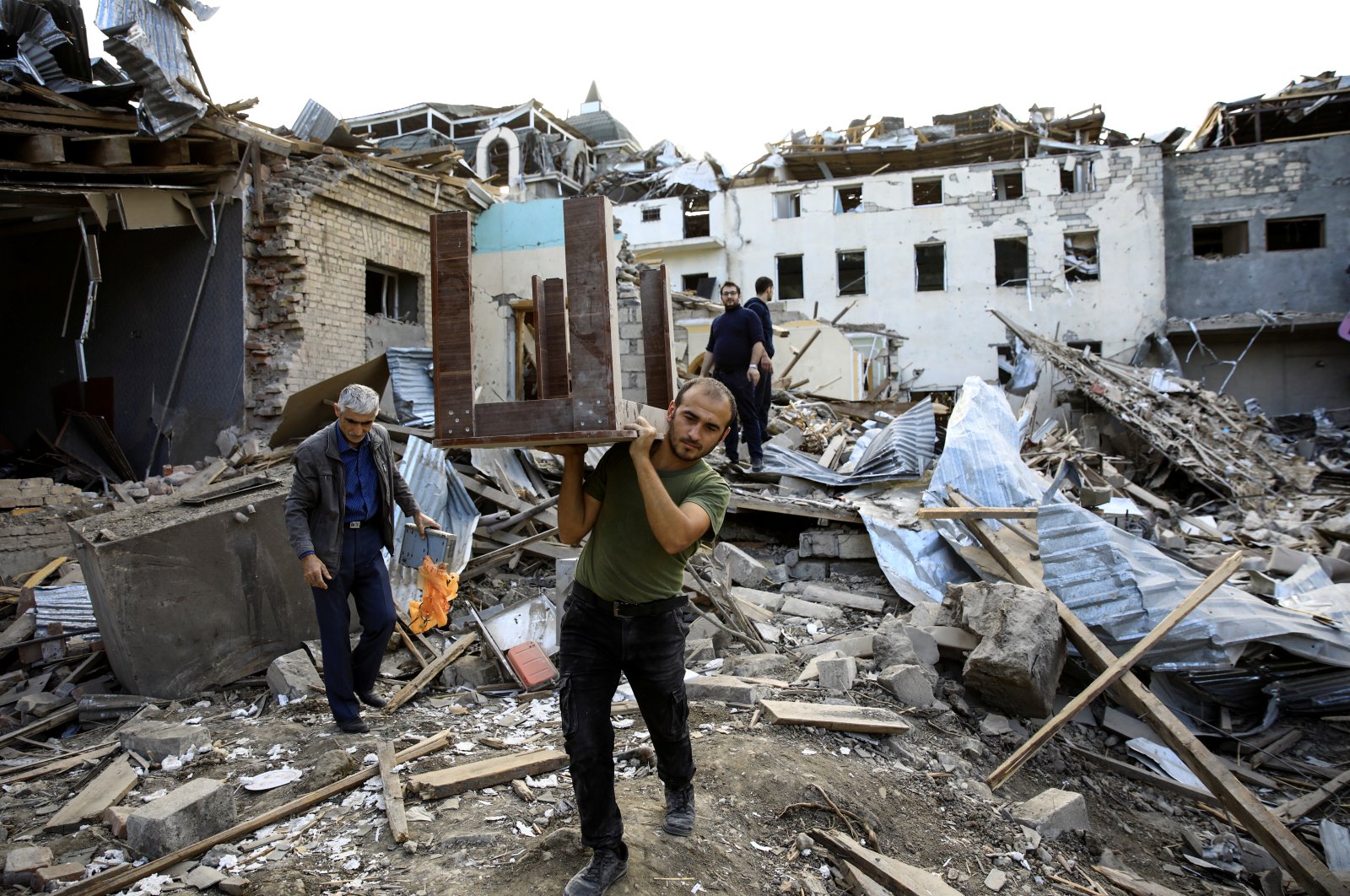 A man carries a table away from ruins at a blast site hit by a rocket during the fighting over the breakaway region of Nagorno-Karabakh in the city of Ganja, Azerbaijan on Oct. 11, 2020. (Reuters Photo)