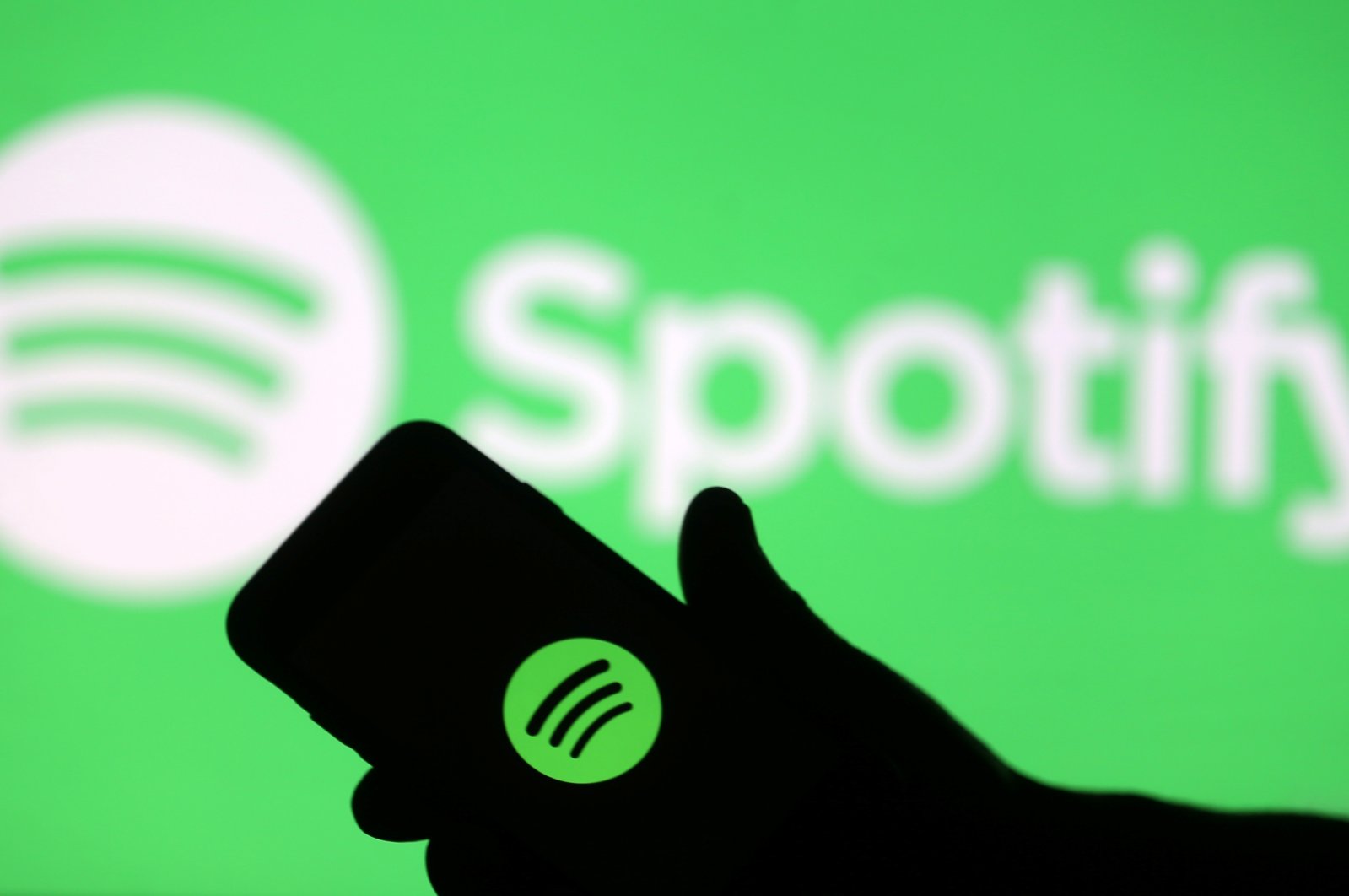 A smartphone is seen in front of a screen projection of the Spotify logo in this picture illustration. (Reuters Photo)