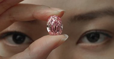 A model displays an ultra-rare 14.83-carat diamond that is one of the largest internally flawless fancy vivid purple-pink gem ever graded by the Gemological Institute of America at a Sotheby's auction room in Hong Kong on Oct. 12, 2020. (AP Photo)