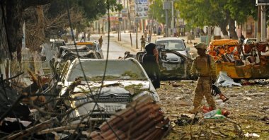 A woman stands next to the military on the scene of a terror attack on the Ambassador Hotel claimed by Somalia's Al-Qaeda-linked Shabaab, in Mogadishu on June 2, 2016. (AFP Photo)