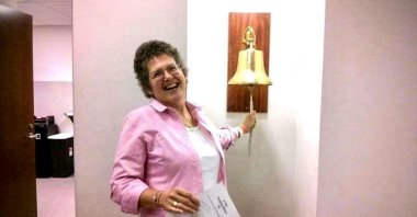 Jill Leach ringing the brass bell of triumph at the chemotherapy ward after completing her rounds of treatment. (Photo courtesy of Jill Leach)