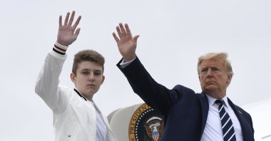 President Donald Trump (R), and his son Barron Trump wave from the top of the steps to Air Force One at Morristown Municipal Airport in Morristown, N.J, Aug. 16, 2020. (AP Photo)