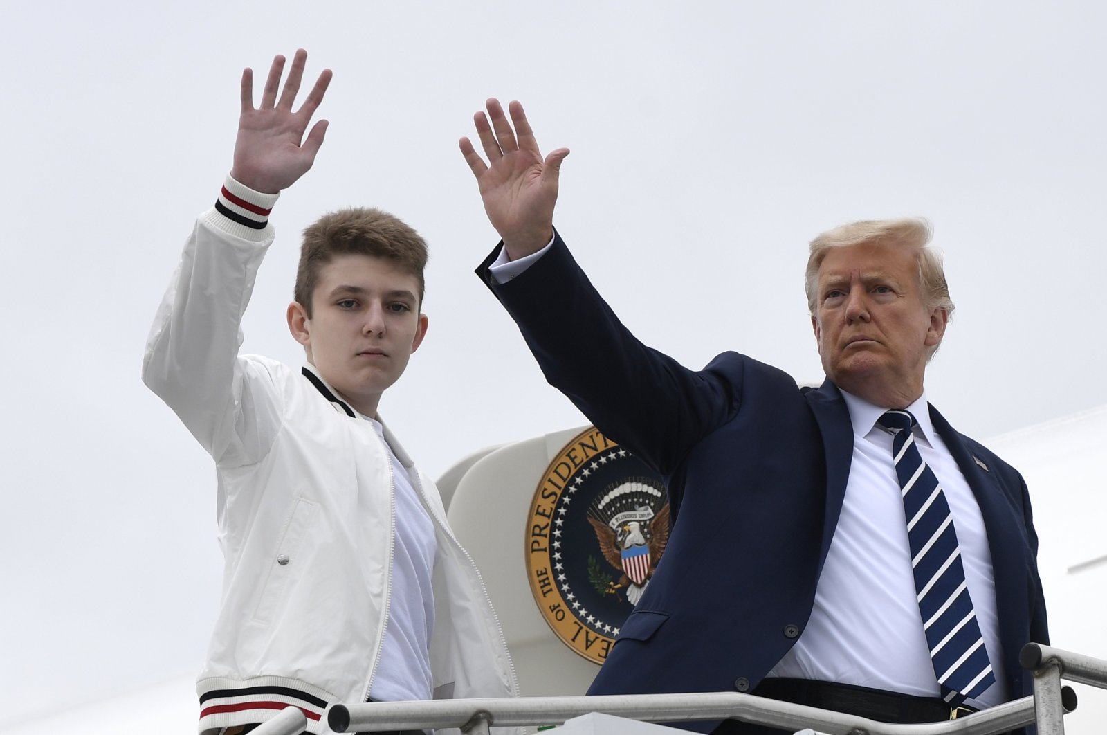 President Donald Trump (R), and his son Barron Trump wave from the top of the steps to Air Force One at Morristown Municipal Airport in Morristown, N.J, Aug. 16, 2020. (AP Photo)