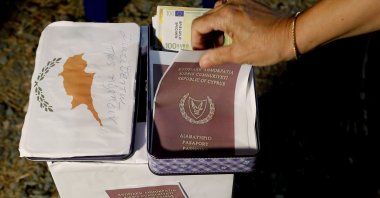 A demonstrator takes a mock copy of a Cyprus passport during a demonstration against corruption outside of the conference center, Nicosia, Oct. 14, 2020. (AP Photo)
