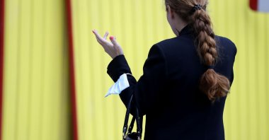 A woman wears her face mask on her arm, in Prague, Czech Republic, Oct. 6, 2020. (AP Photo)