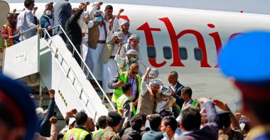 Freed Yemeni Houthi prisoners wave to the crowd as they descend the stairs of the plane that transported them after being released as the war-torn country began swapping 1,000 prisoners in a complex operation overseen by the International Committee of the Red Cross, Sanaa, Yemen, Oct. 15, 2020. (AFP Photo)