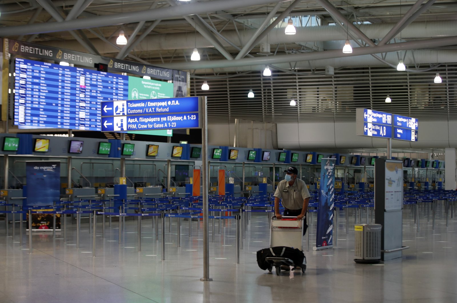 A passenger wearing a face mask walks through the empty Eleftherios Venizelos International Airport during a 24-hour strike in the public sector in Athens, Greece, Oct. 15, 2020. (AP Photo)