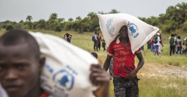People carry food aid from the United Nations World Food Program agency, Dec. 7, 2014. (AP Photo)