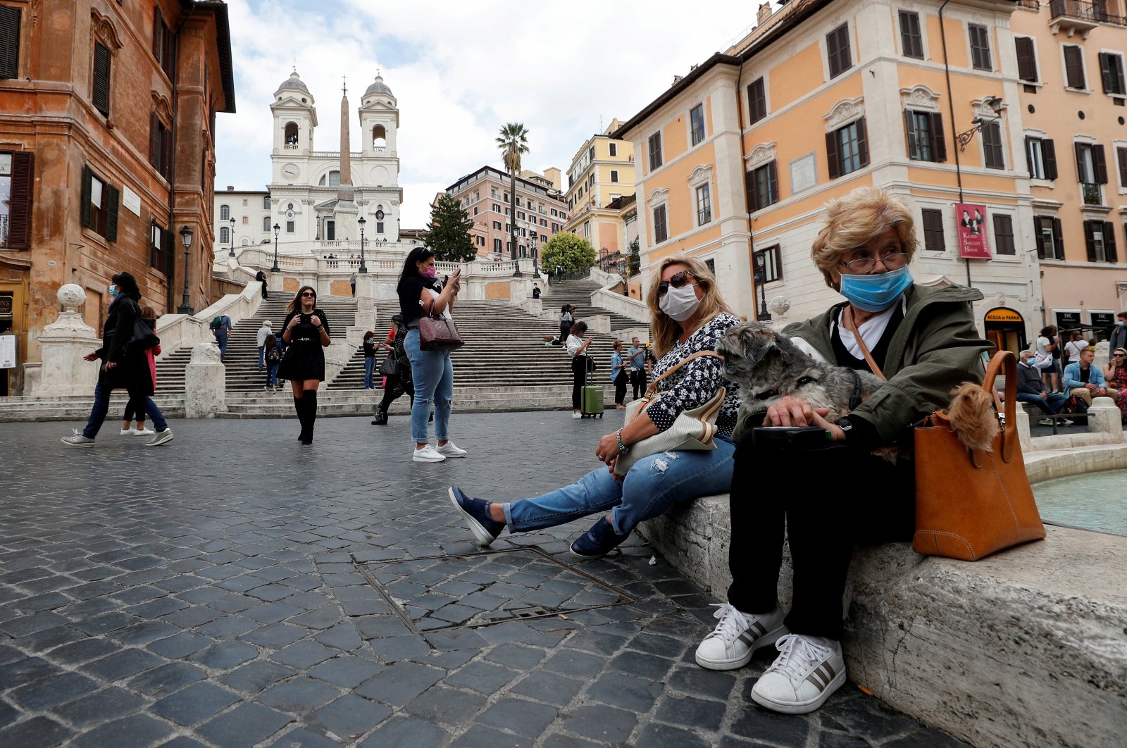 Women wearing face masks sit next to the Spanish Steps, as local authorities in the Italian capital Rome order face coverings to be worn at all times out of doors in an effort to counter rising coronavirus disease (COVID-19) infections, in Rome, Italy, Oct. 2, 2020. (Reuters Photo)