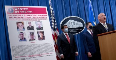 A poster showing six wanted Russian military intelligence officers is displayed as FBI Special Agent in Charge of the Pittsburgh field office Michael Christman (R) accompanied by Assistant Attorney General for the National Security Division John Demers (L) and FBI Deputy Director David Bowdich, (2nd R), speaks at a news conference at the Department of Justice, in Washington, DC, U.S., Oct. 19, 2020. (EPA Photo)