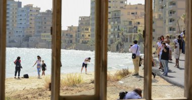 Journalists and the public are seen through a window frame at the beach lined with abandoned hotels, after the reopening of Varosha, in the fenced-off area of Gazimağosa (Famagusta), TRNC, Oct. 8, 2020. (AP Photo)