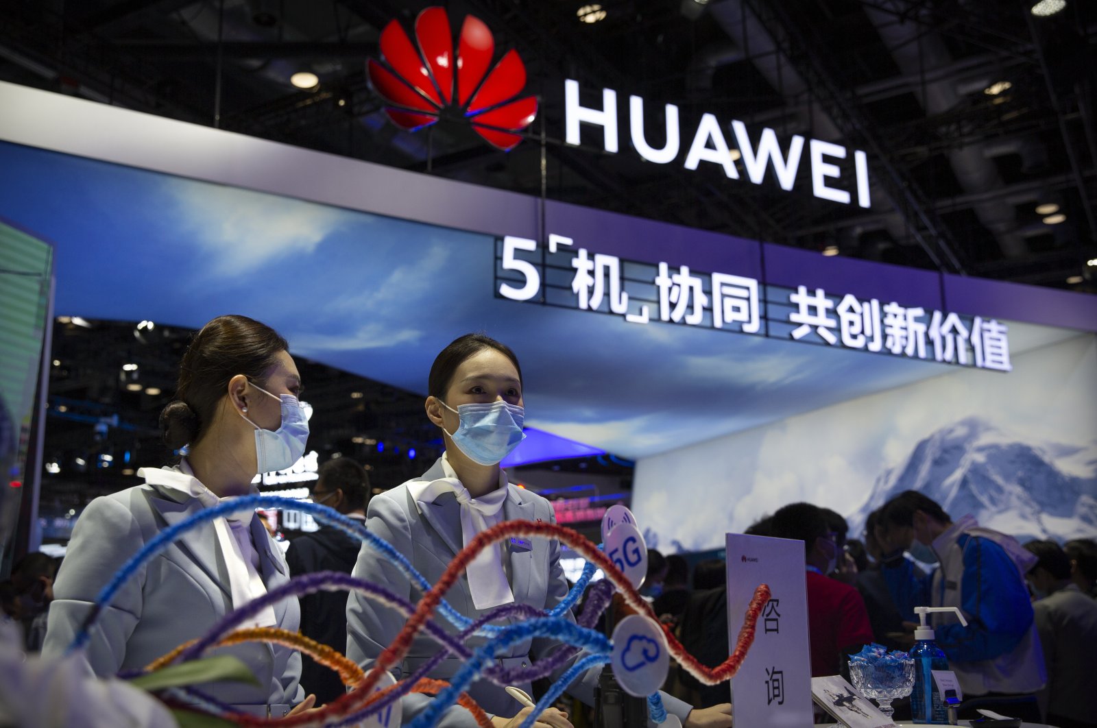Staff members wearing masks to protect against the coronavirus stand at a booth from Chinese technology firm Huawei at the PT Expo in Beijing, Oct. 14, 2020. (AP Photo)