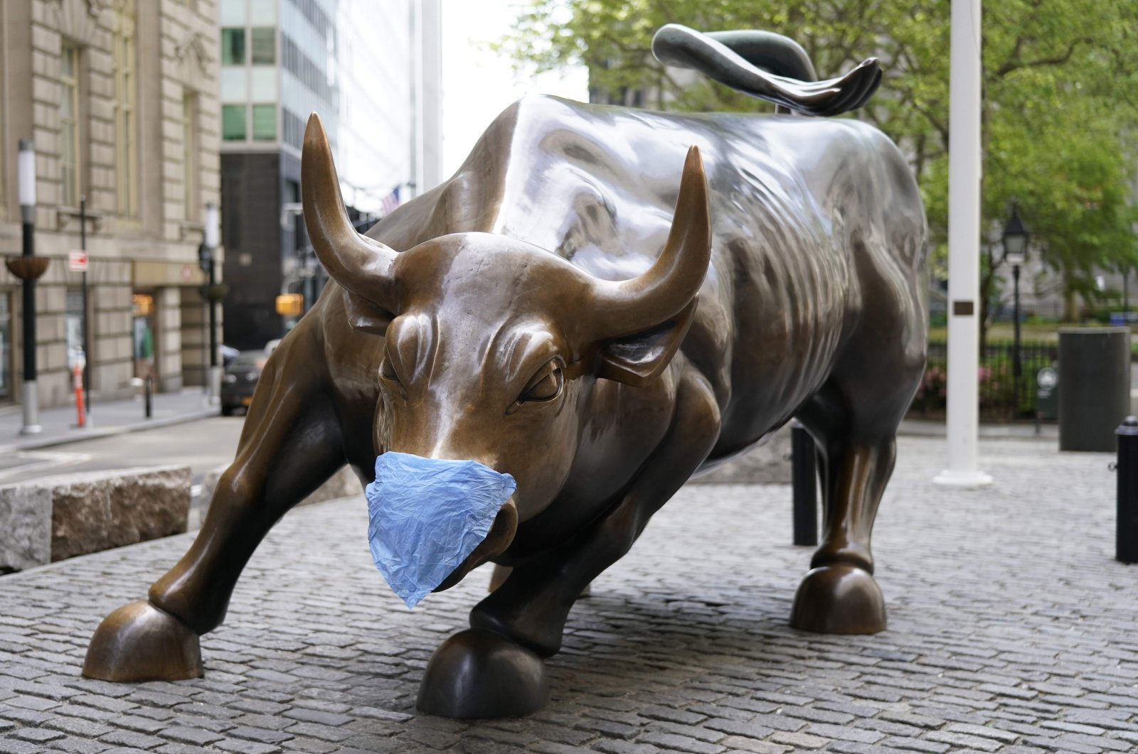 The Charging Bull, sometimes referred to as the Wall Street Bull, in the Financial District of Manhattan with a facemask in New York City, New York on May 19, 2020. (AFP Photo)
