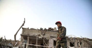 A soldier walks past a destroyed house in a residential area that was hit by rocket fire overnight by Armenian forces, early Saturday, Oct. 17, 2020, in Ganja, Azerbaijan's second largest city, near the border with Armenia. (AP Photo)