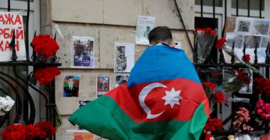 A man holding the national flag of Azerbaijan stands next to a makeshift memorial for people killed in the country during the military conflict over the occupied region of Nagorno-Karabakh, outside the Embassy of Azerbaijan in Moscow, Oct. 19, 2020. (Reuters Photo)