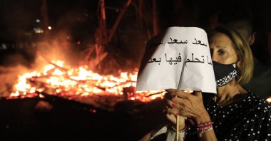 A protester holds an Arabic placard that reads: "Saad don't dream on it any more," Beirut, Oct. 21, 2020. (AP Photo)