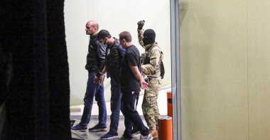 A gunman with a weapon in his hand, escorts three police officers, who surrendered themselves as hostages, out of the bank building in the town of Zugdidi in western Georgia, Oct. 21, 2020. (AP Photo)
