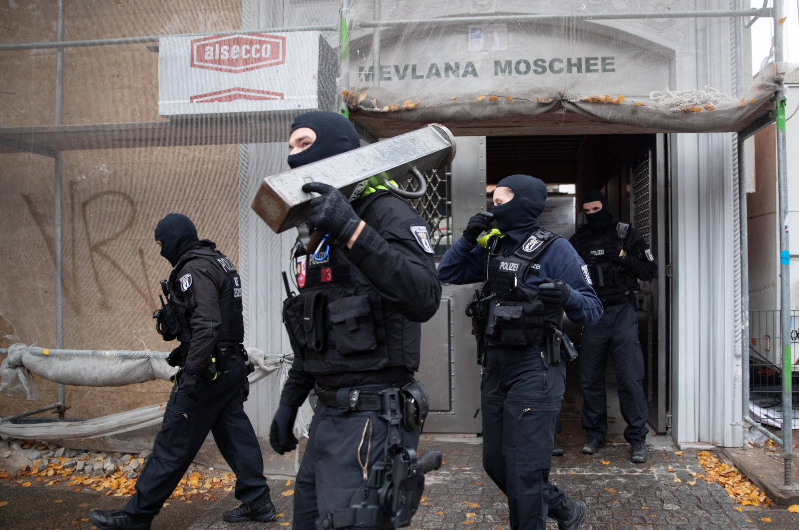 Police officers carry a metal bar to break doors in front of the entrance of Mevlana Mosque in Berlin-Kreuzberg during a police raid, in Berlin, Germany, Oct. 21, 2020. (EPA Photo)