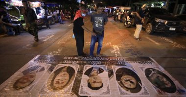 Pro-democracy protesters look on the pictures (R-L) the Prime Minister Prayut Chan-o-cha, the Deputy Prime Minister General Prawit Wongsuwan and members of the House of Representative, Paiboon Nititawan, Pareena Kraikupt and the founder of a pro-royalist group 'Thai Pakdee' (Loyal Thai) Warong Dechgitvigrom on the road ground as the block a road during an anti-government protest outside the Bangkok Remand Prison in Bangkok, Thailand, 24 Oct. 2020. (EPA Photo)