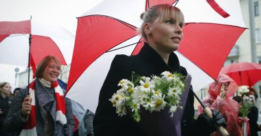 Belarusian women with umbrellas in the colors of the old Belarusian national flag attend an opposition rally to protest the official presidential election results in Minsk, Belarus, Saturday, Oct. 24, 2020. (AP Photo)